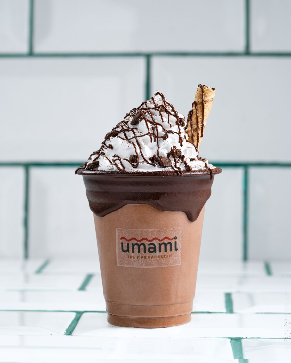 A thick dark chocolate shake topped with whipped cream, chocolate sauce and a wafer stick.