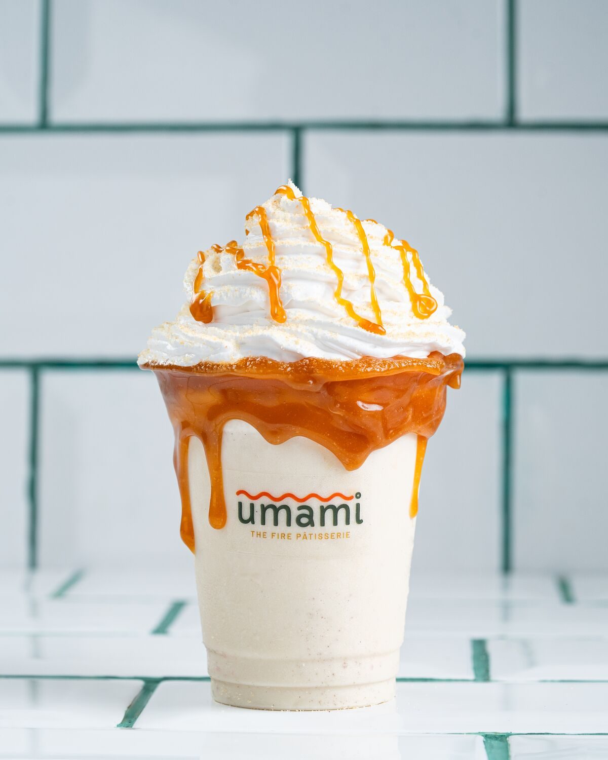 A pale salted caramel shake topped with whipped cream and caramel sauce running down the side of the cup.