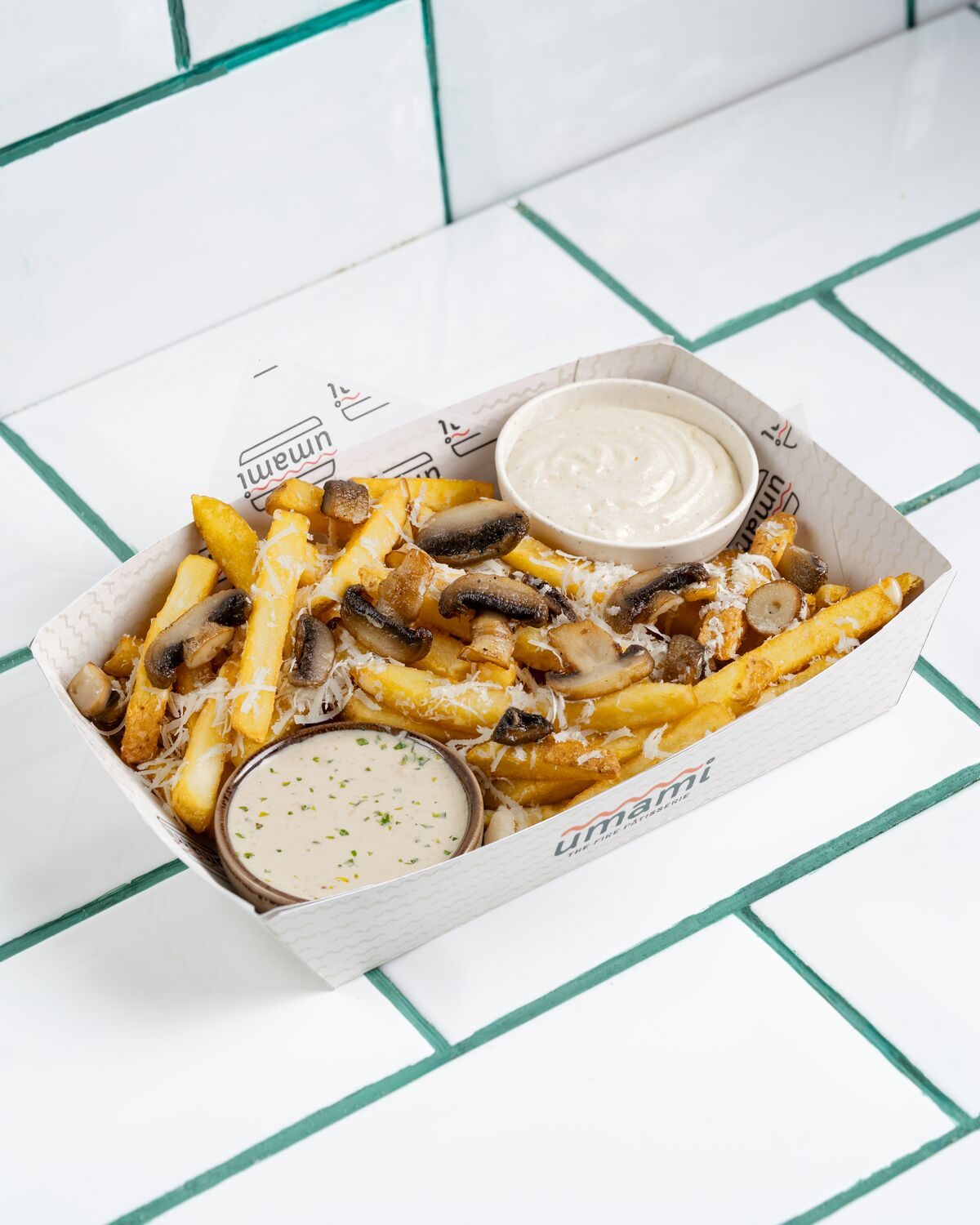 Fries tossed with sauteed mushrooms in a creamy truffle sauce, served with a pot of white dip, shot at a forty five degree angle.
