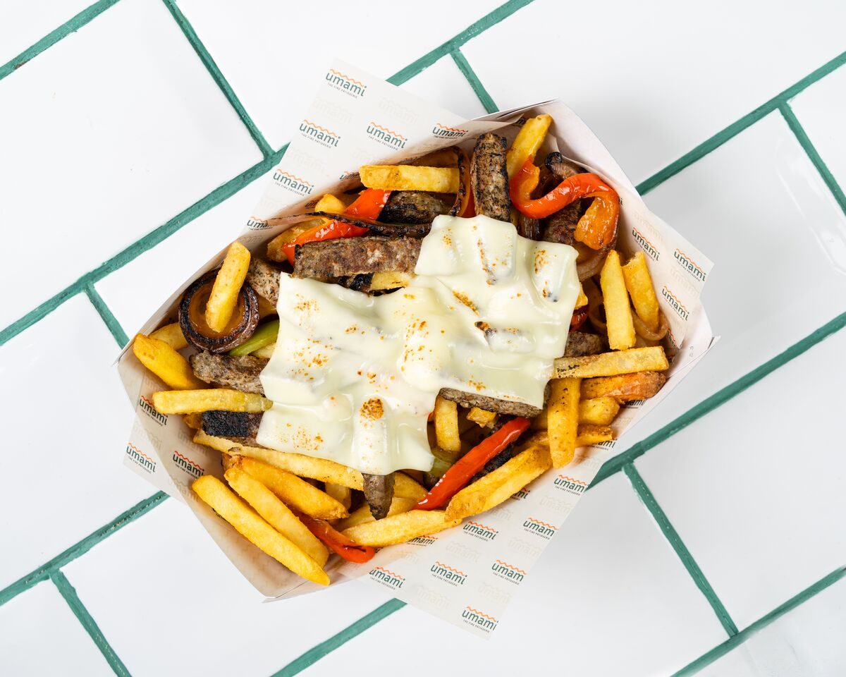Fries piled with strips of grilled meat and red and yellow peppers under slices of melted white cheese, shot from directly overhead.